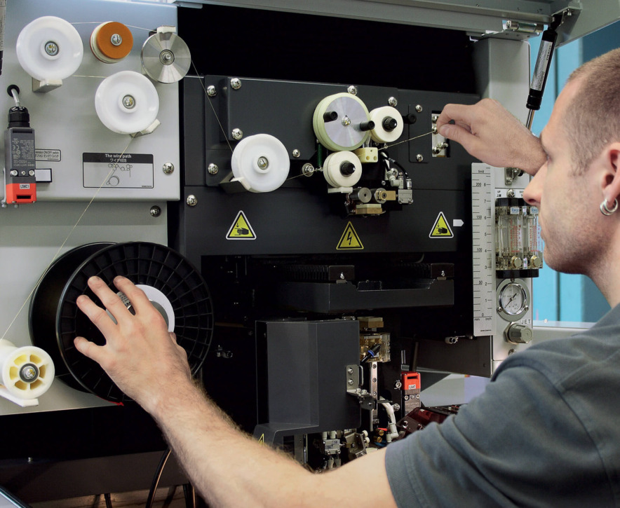 Franz Stebler replaces the wire spool and correctly feeds the wire around several pulleys.