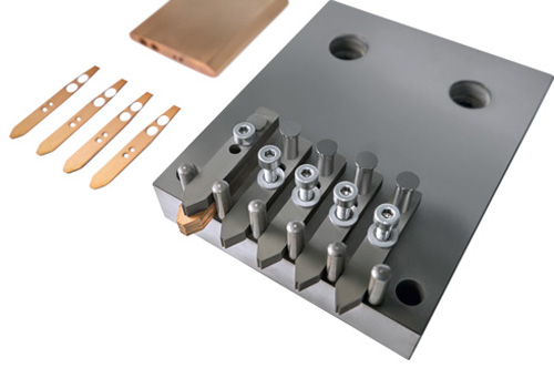 Contact pins for electric plugs are cut from the block.